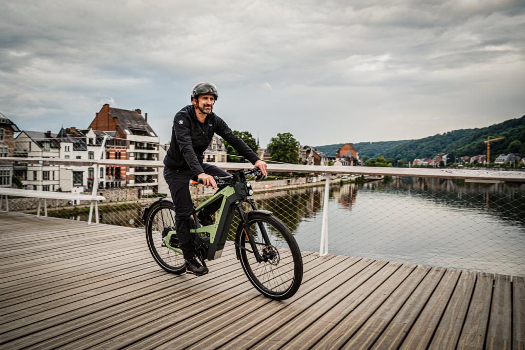 Man with E-bike rides over wooden bridge over river